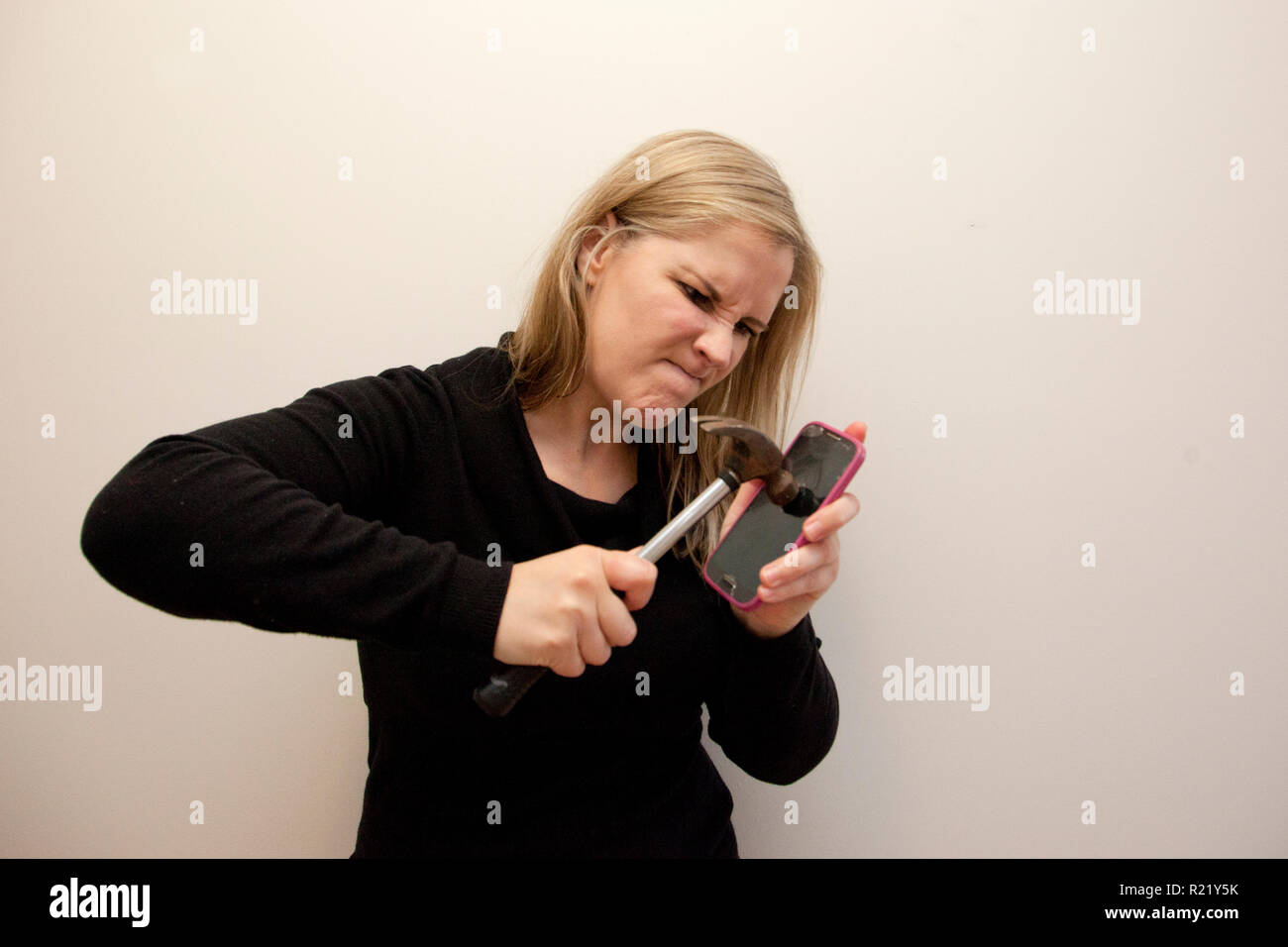 Woman is determined to break into her cell phone with a hammer Stock Photo  - Alamy