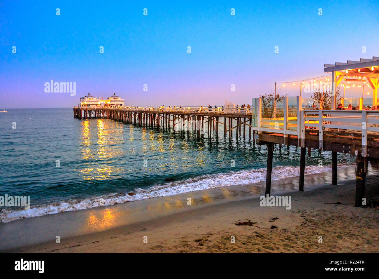 Scenic coastal landscape illuminated by night of Malibu Pier in Malibu, California, United States see from Carbon Beach. Malibu Pier is an historic landmark. Blue hour shot. Copy space. Stock Photo