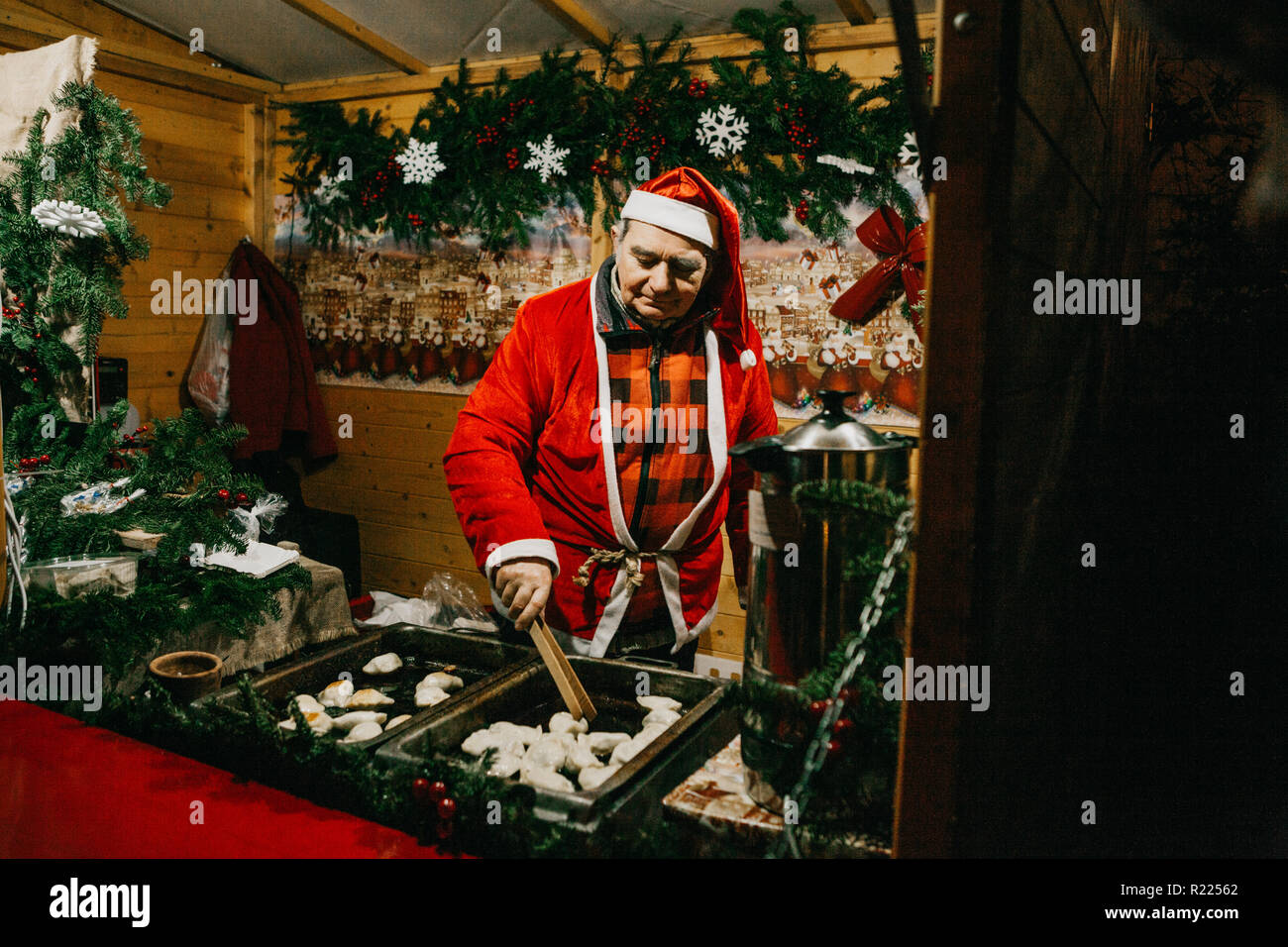 Warsaw, December 25, 2017: A seller dressed as Santa Claus sells fast food at a traditional Christmas night market in Warsaw. Stock Photo