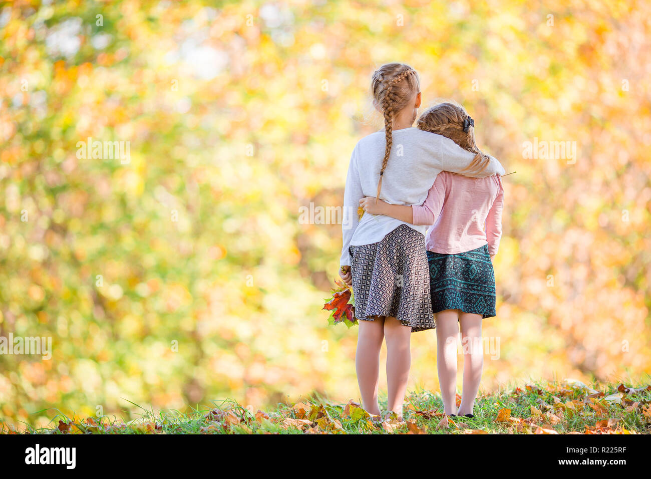 Little adorable girls at warm day in autumn park outdoors Stock Photo ...
