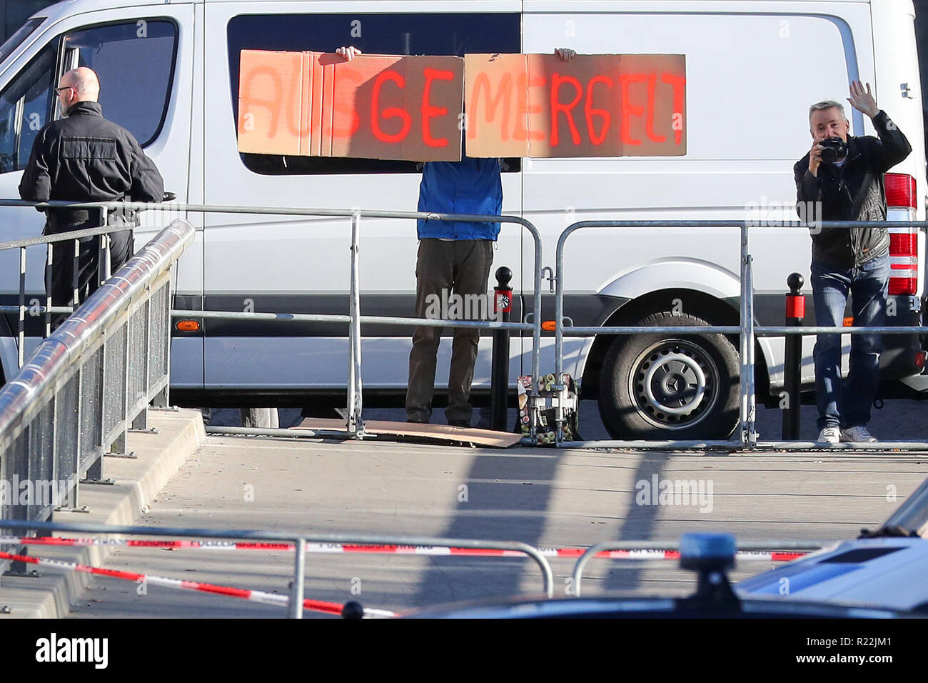 Chemnitz, Germany. 16th Nov, 2018. A man holds a self-painted cardboard sign 'Emaciated' behind a police barrier and the Chancellor's official car up in front of the Hartmannhalle in Chemnitz. Federal Chancellor Merkel (CDU) is currently attending the training of the junior teams of the second division basketball team Niners Chemnitz. A meeting with citizens is then scheduled. The Chancellor's visit to Chemnitz was prompted by a deadly knife attack on a German about three months ago and subsequent demonstrations with xenophobic attacks. Credit: Jan Woitas/dpa-Zentralbild/dpa/Alamy Live News Stock Photo