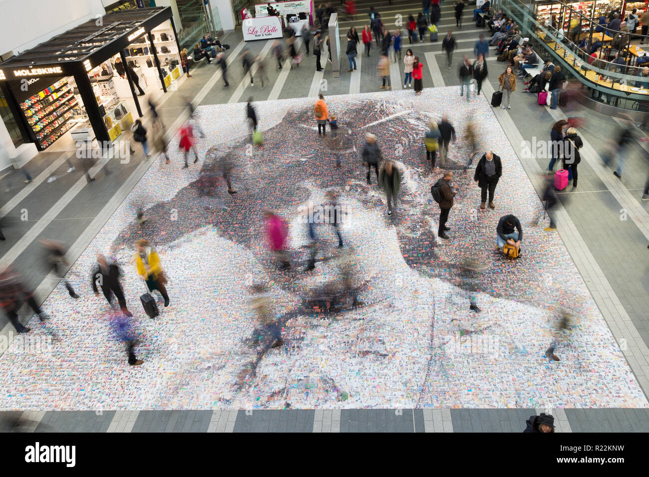 Birmingham, UK. 16th November, 2018. A large-scale mosaic portrait of sufragette Hilda Burkitt is on show on the concourse floor of New Street station, Birmingham. The 20 metre portrait is made up of 3,724 selfie photographs and other photographs of women sent in from all over the UK. The project, called Face of Suffrage, is deisgned by artist Helen Marshall. Hilda Burkitt was born in Wolverhampton in 1876, was convicted and jailed for breaking a window in the then Prime Minister's train carriage. Peter Lopeman/Alamy Live News Stock Photo
