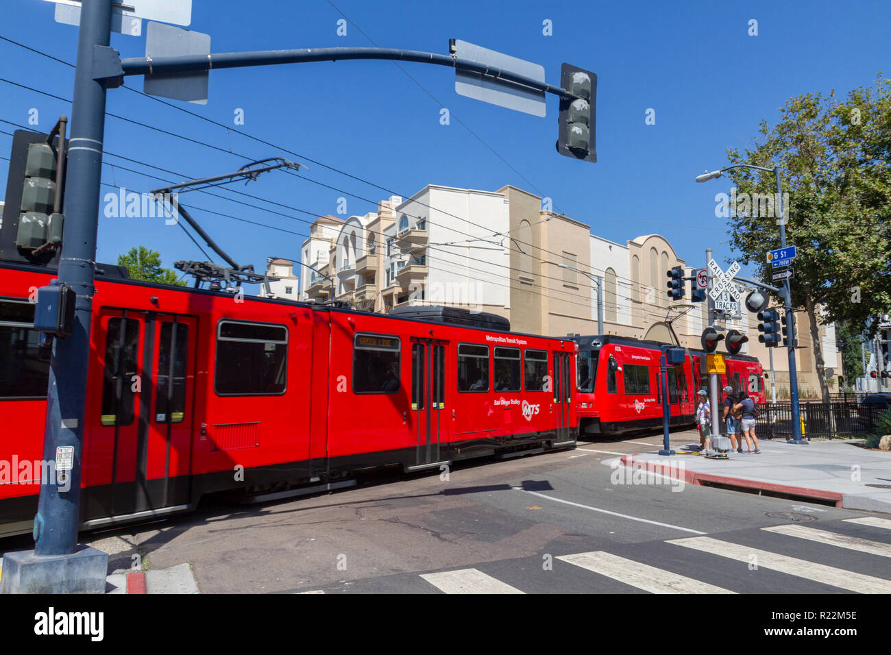 A Green Line MTS Trolley (San Diego Metropolitan Transit System) crossing a railroad crossing in San Diego, California, United States. Stock Photo