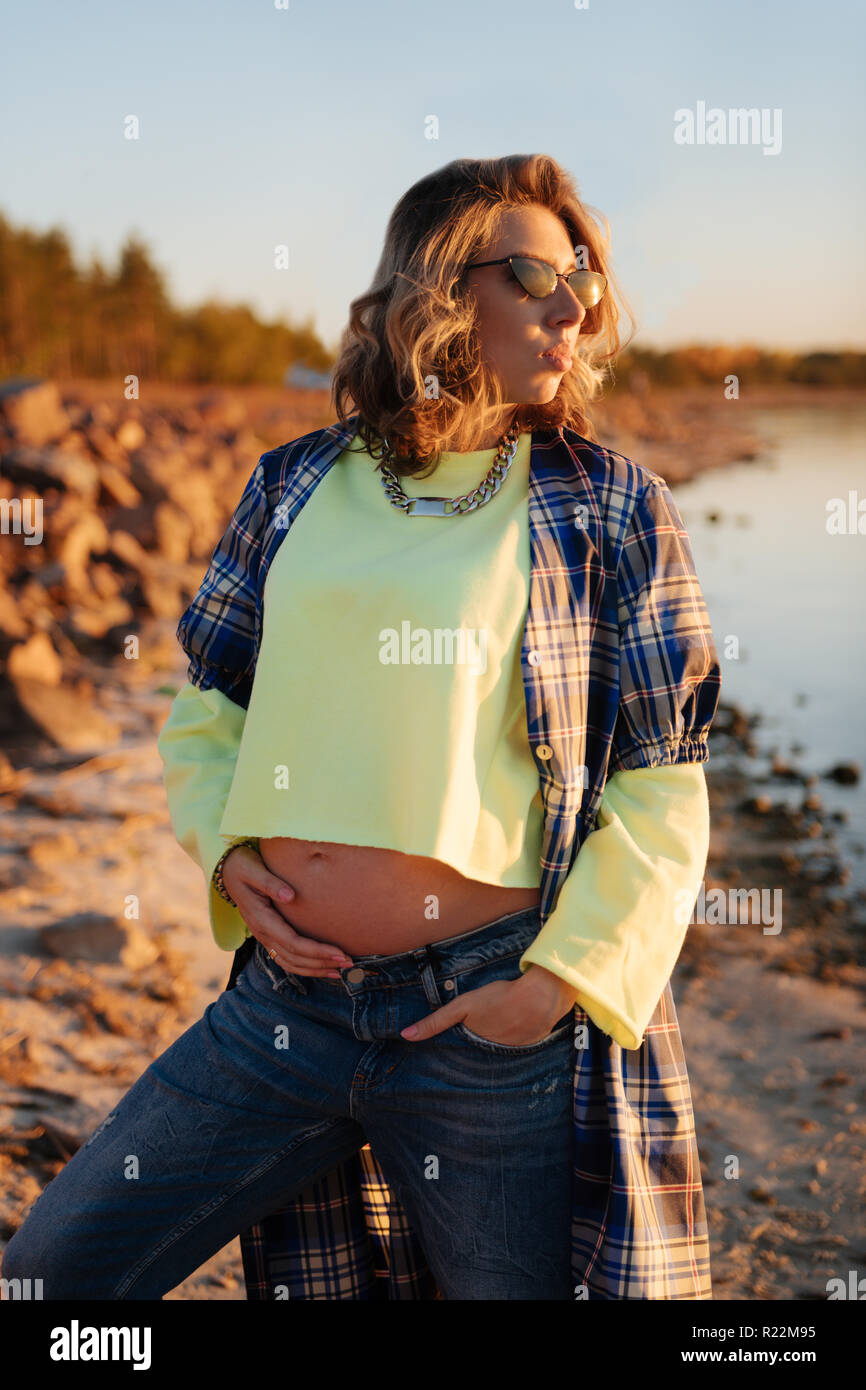 Stylish pregnant woman wearing sunglasses during the sunset Stock Photo