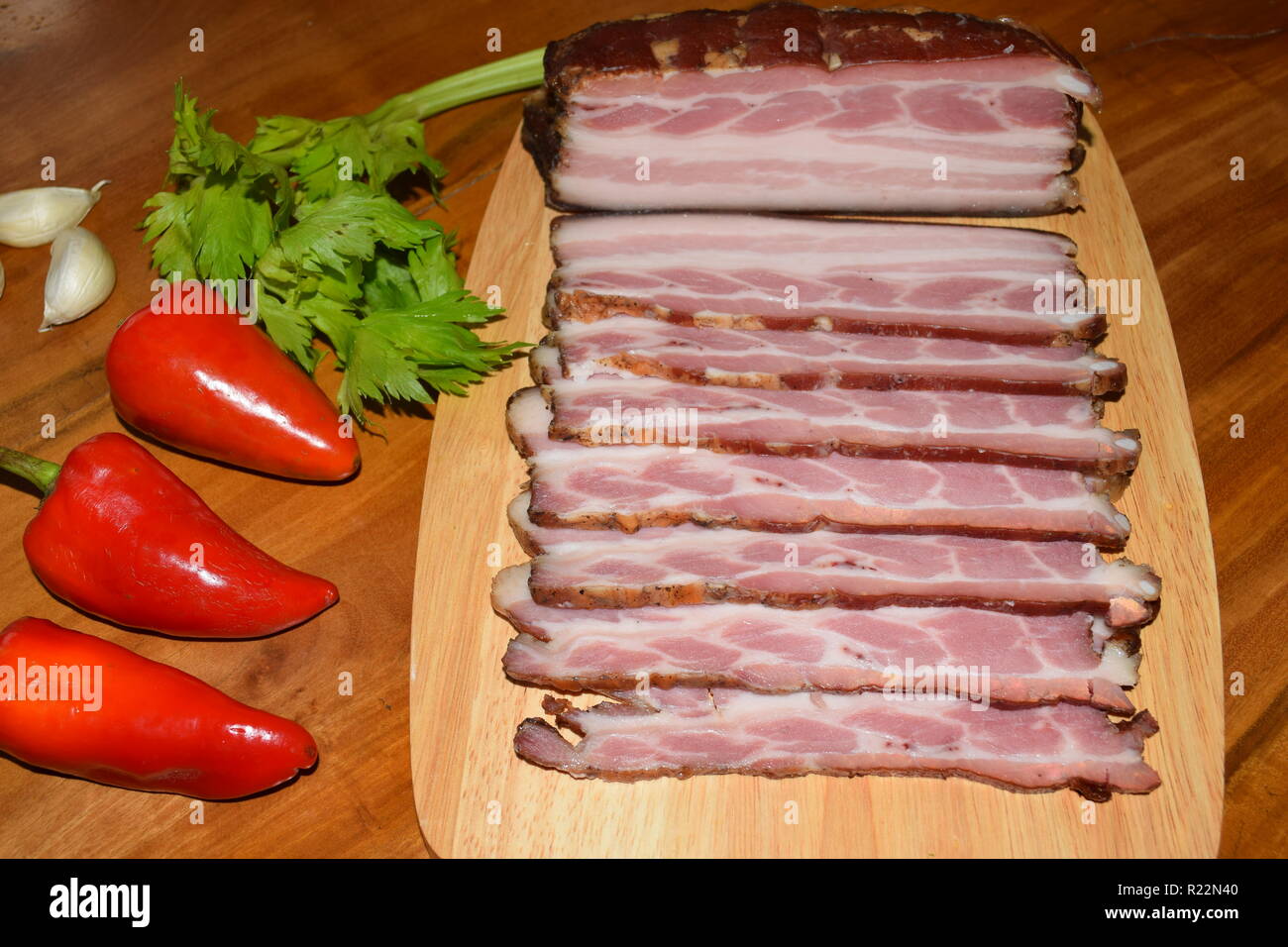The whole of fame of 'Smoked Bacon'  German – Food, fully cured and smoked pork bacon on wooden plate according to grandmother's recipe and art. Stock Photo