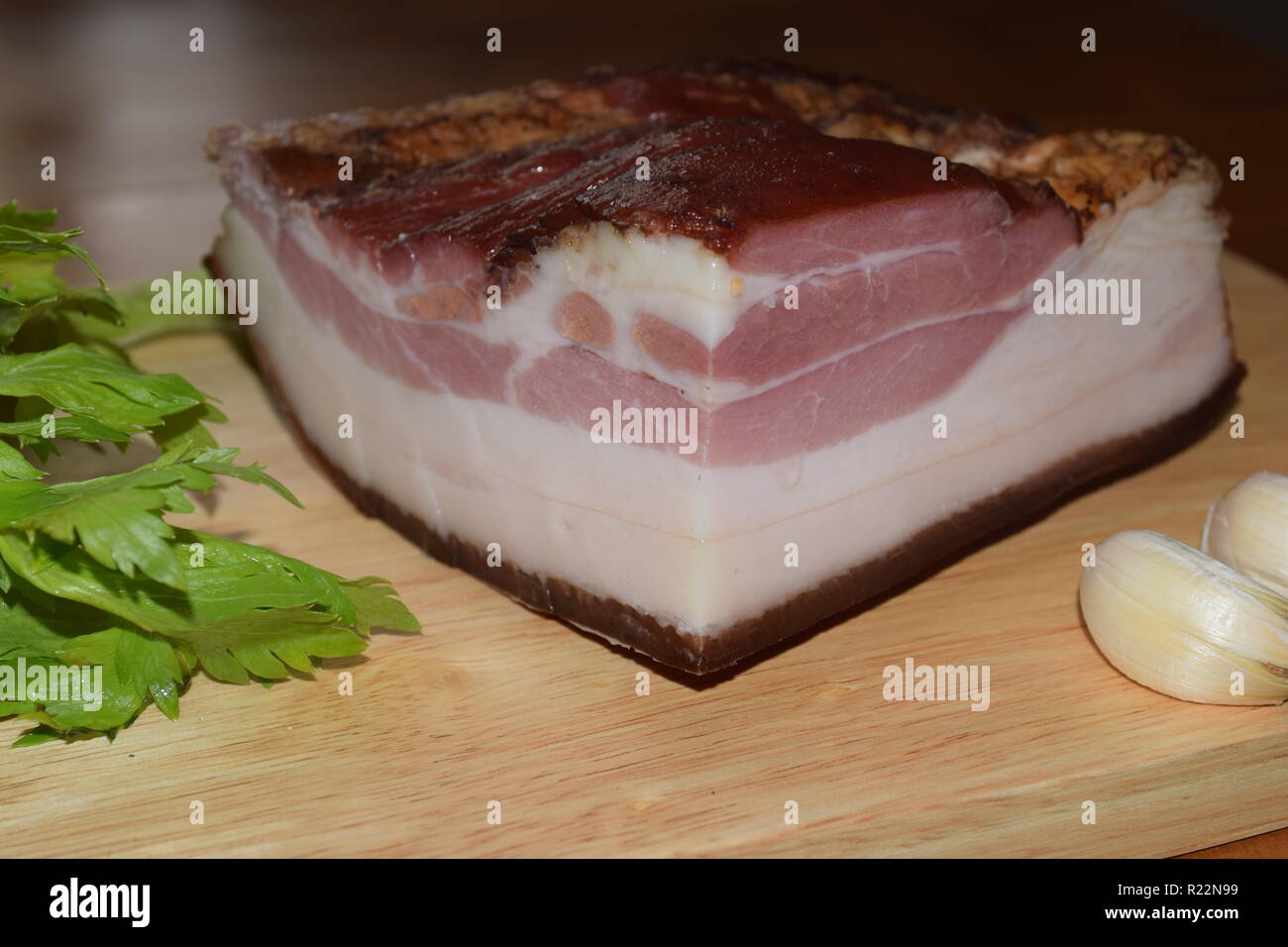 The whole of fame of 'Smoked Bacon'  German – Food, fully cured and smoked pork bacon on wooden plate according to grandmother's recipe and art. Stock Photo