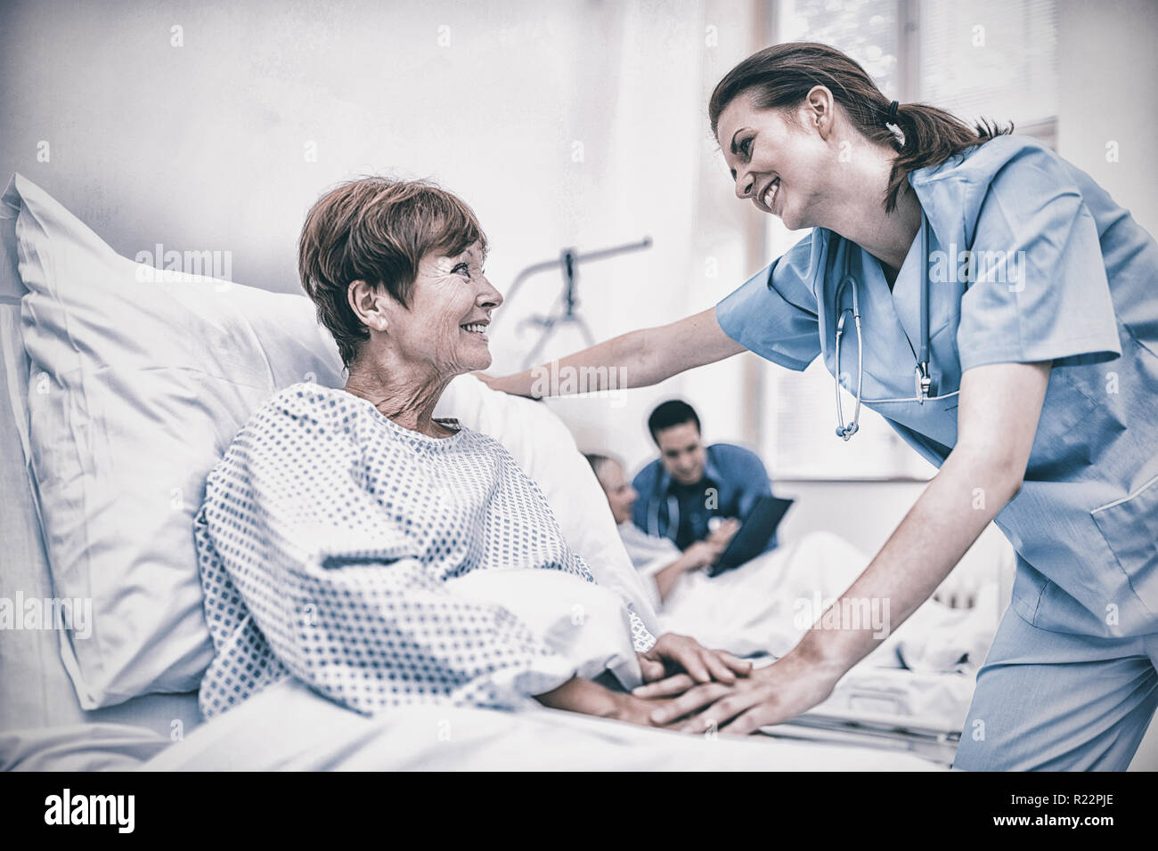 Nurse consoling a patient in hospital ward Stock Photo
