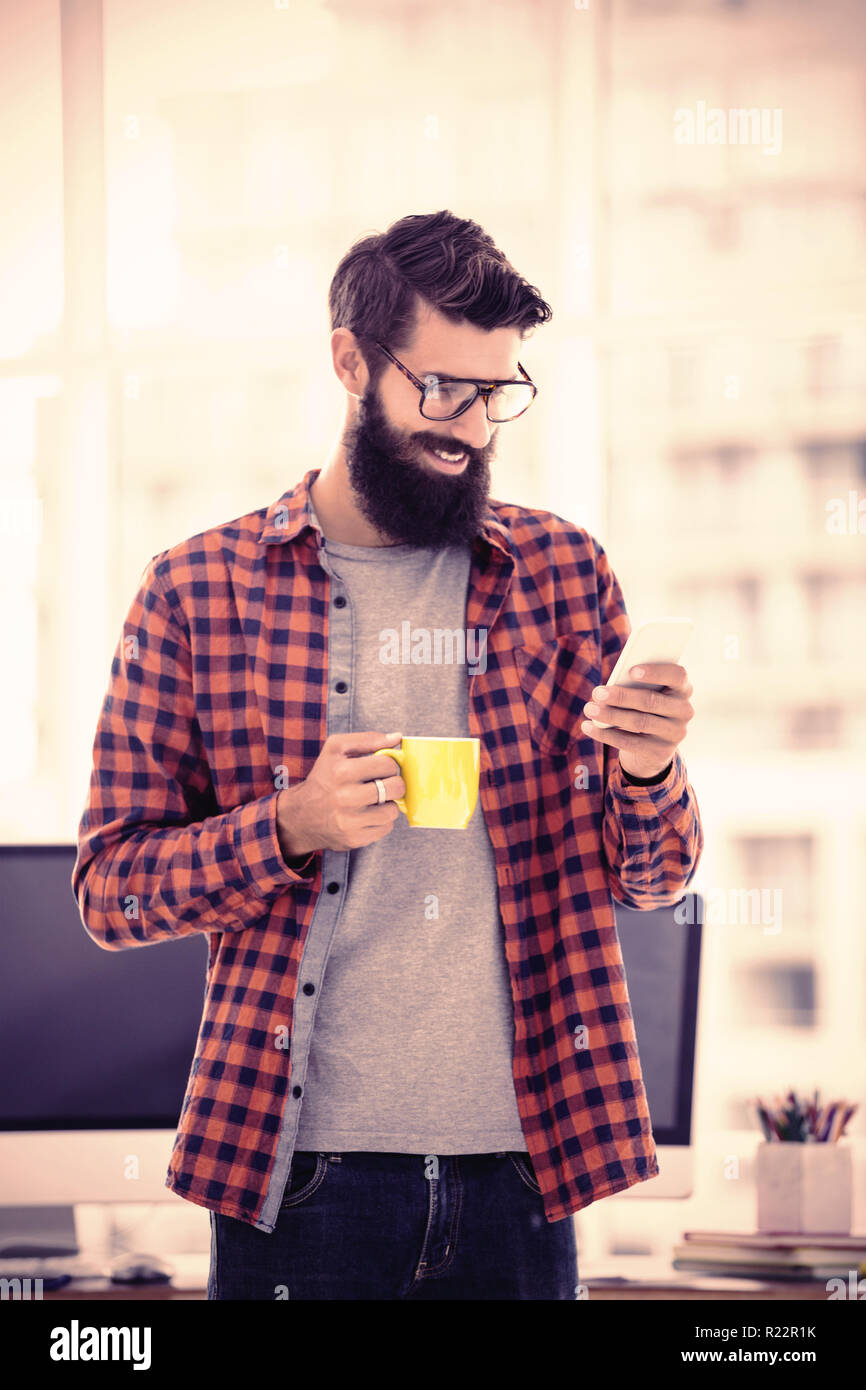 Hipster using smartphone and drinking coffee Stock Photo