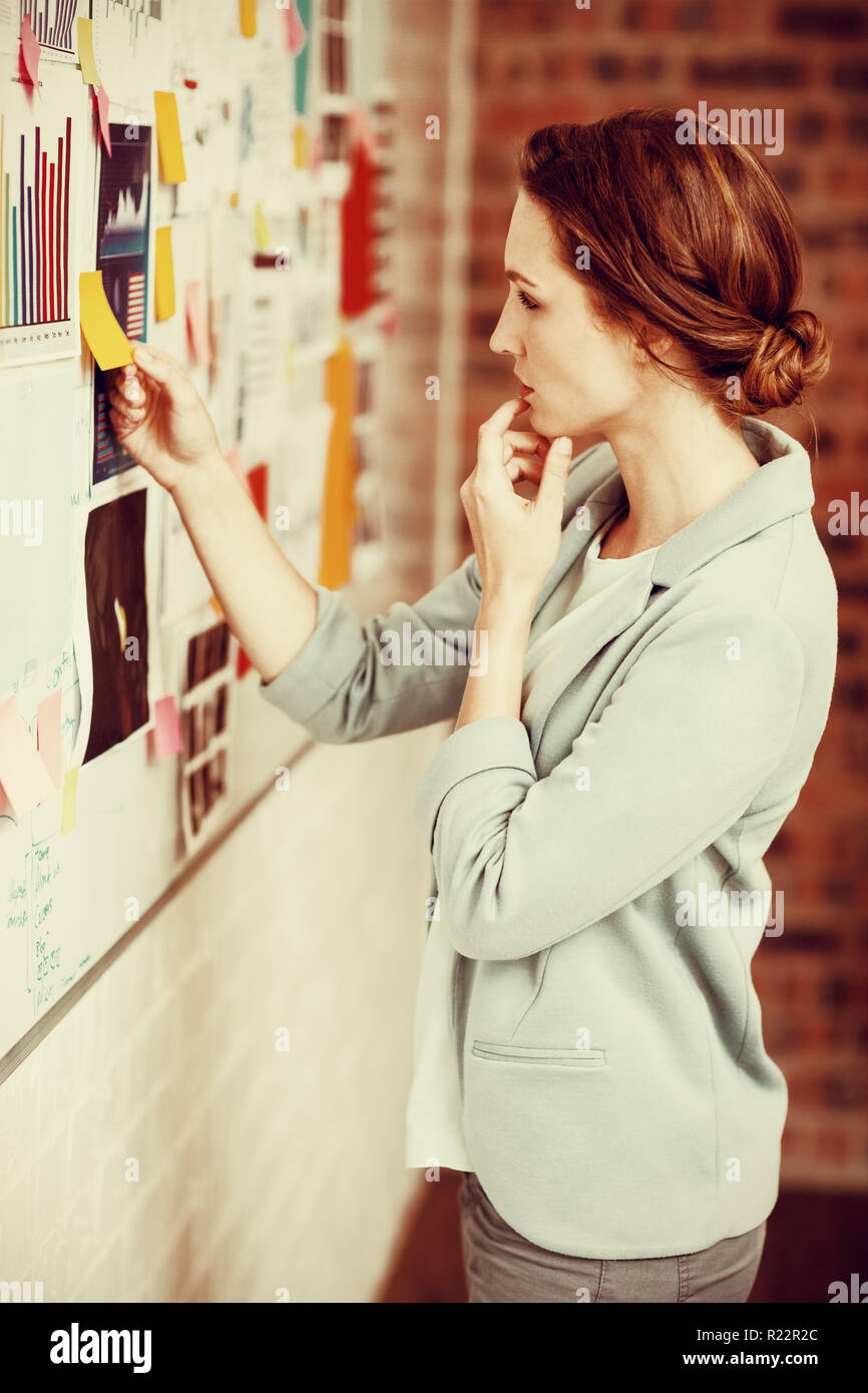 Businesswoman putting sticky notes on whiteboard Stock Photo - Alamy