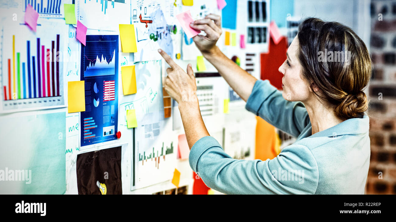 Businesswoman putting sticky notes on whiteboard Stock Photo - Alamy