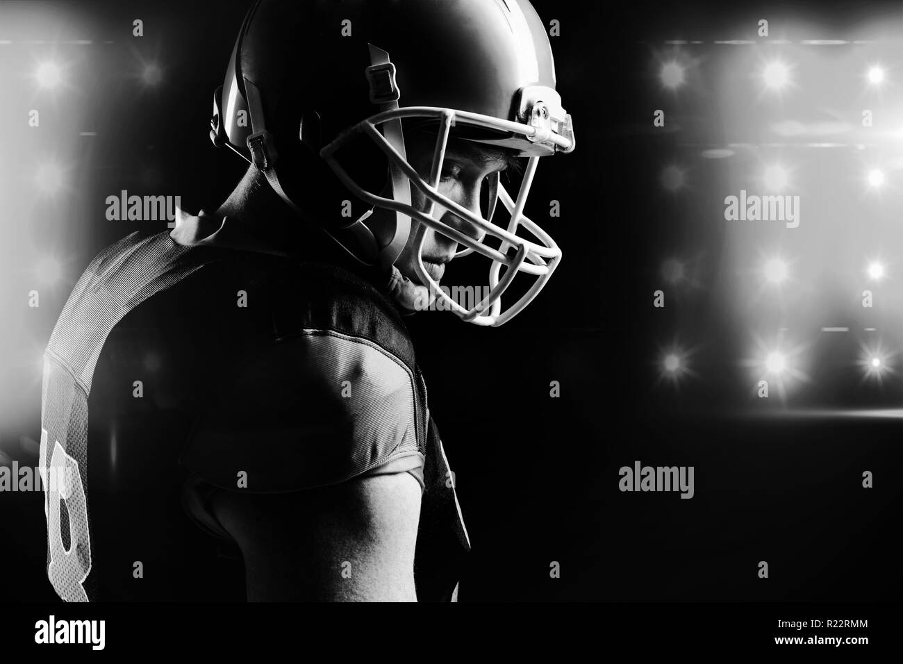 American football player in helmet standing against black background
