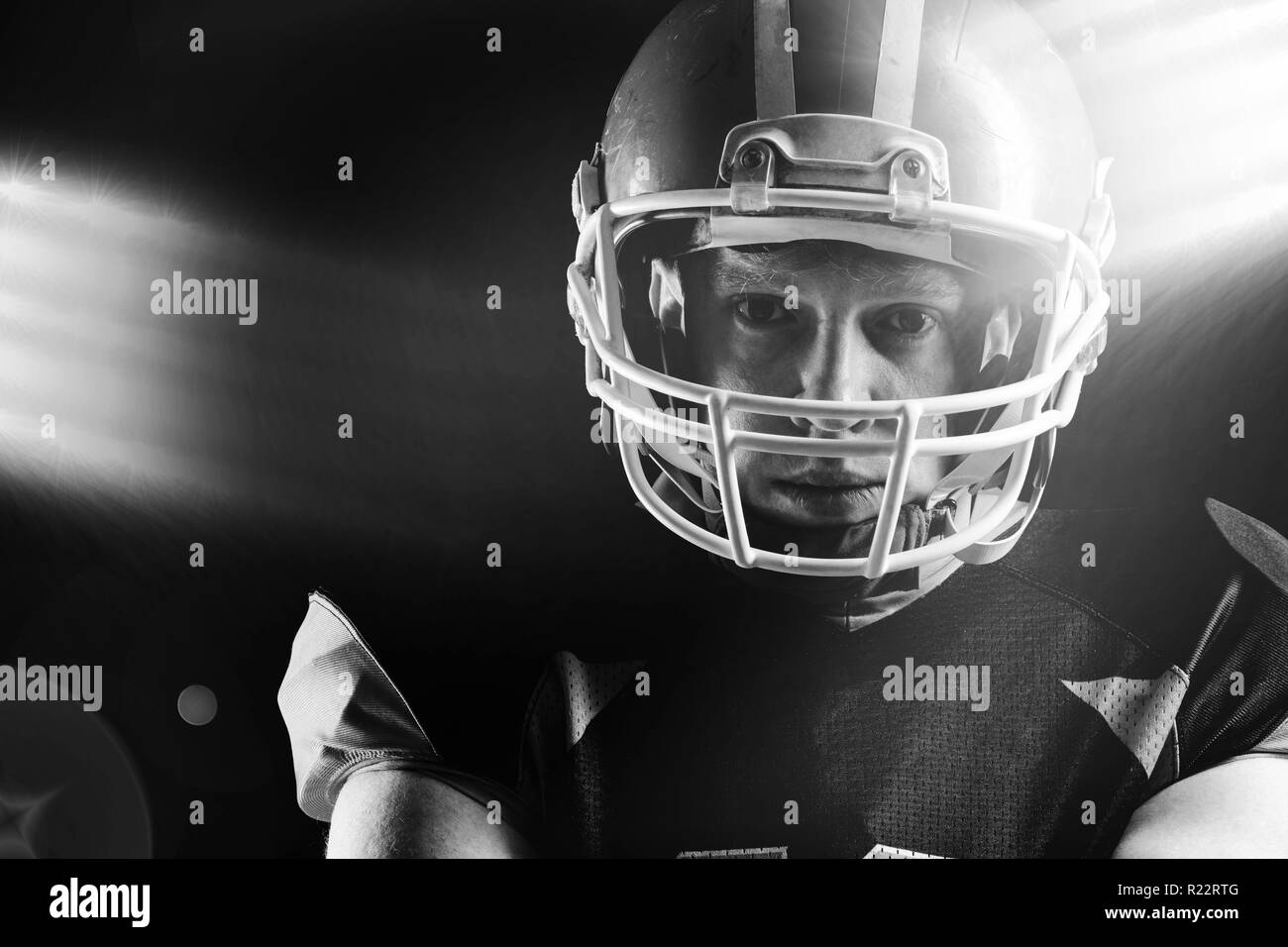 American football player in helmet standing against black background