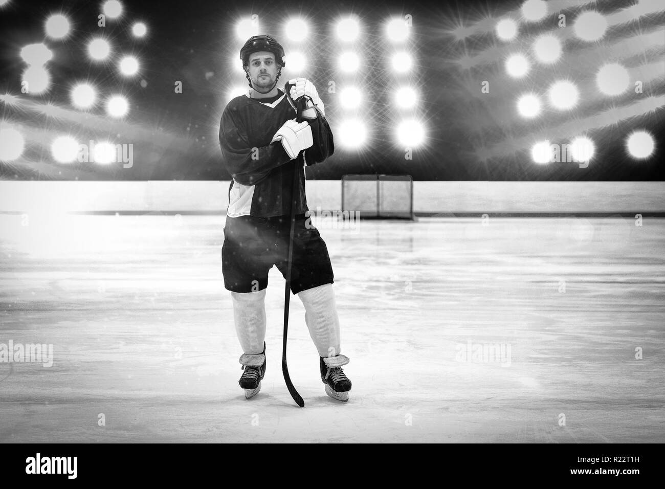 Composite image of hockey player with hockey stick standing on rink Stock Photo