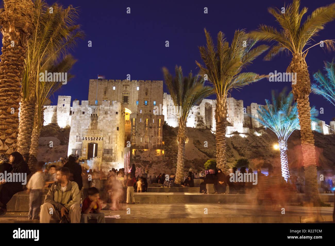 Aleppo, Aleppo Governorate, Syria : People sit outside the Illuminated Citadel of Aleppo, a large medieval fortified palace in the centre of the old c Stock Photo