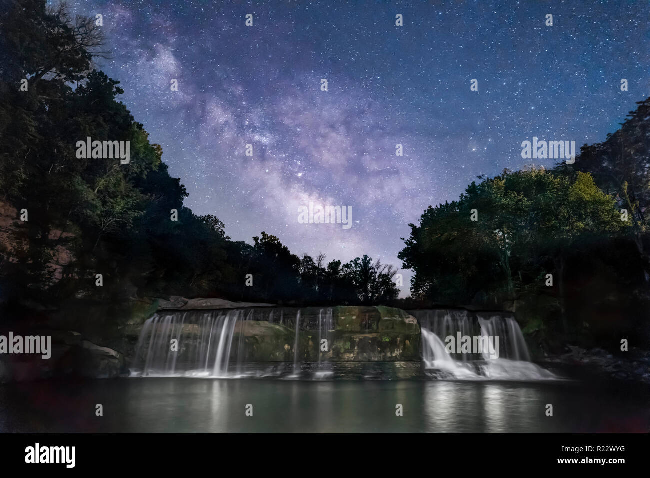 The Milky Way shines brightly in the dark rural Indiana sky over Owen County, Indiana's Upper Cataract Falls. Stock Photo