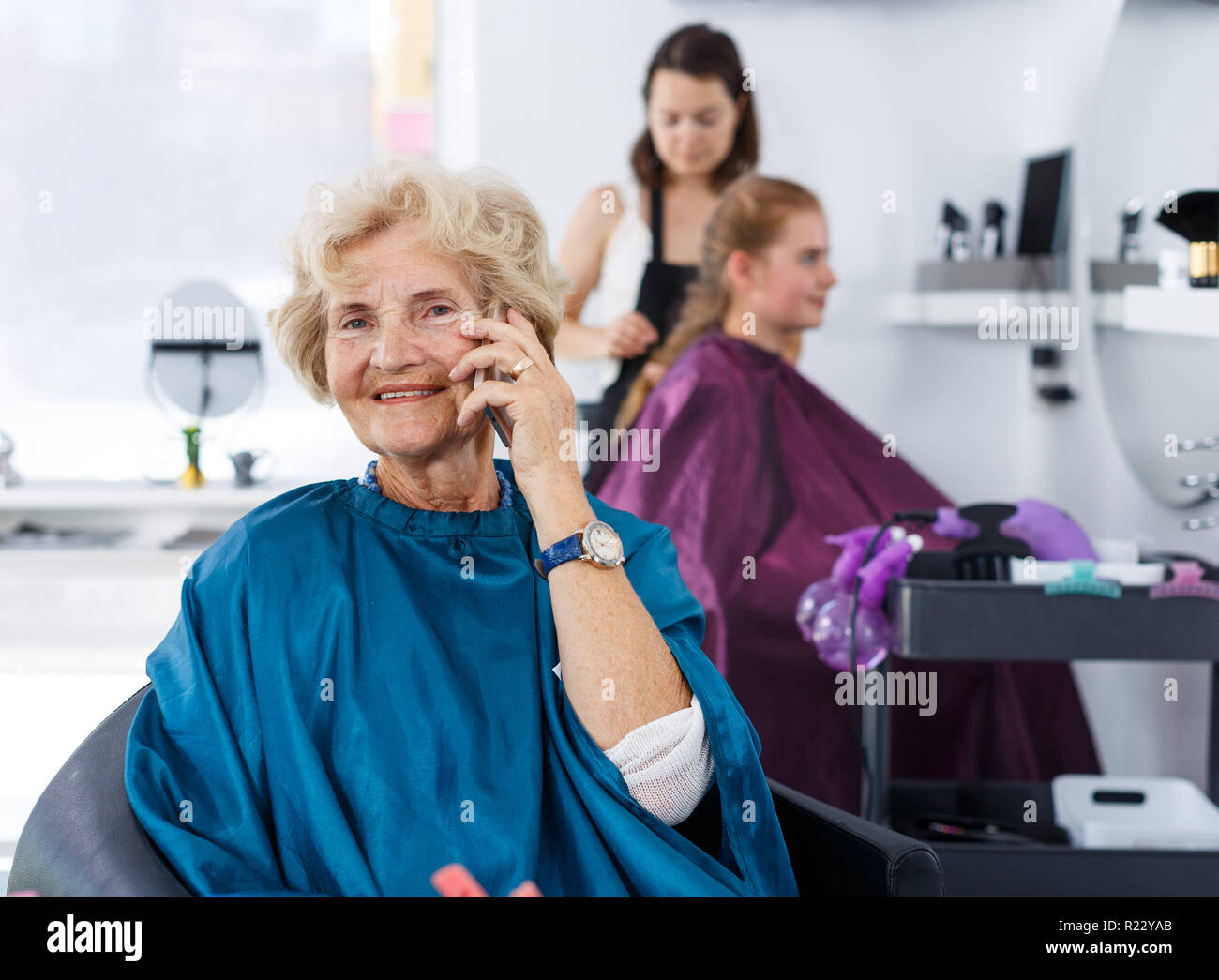 Portrait of elderly female client waiting for hair styling in modern