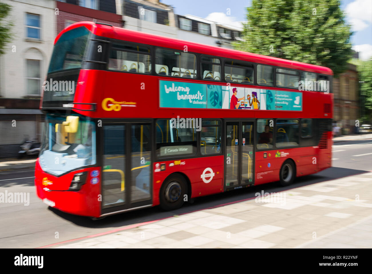 Panning image of a red double decker bus as it travels along a road in London on a sunny day, London, UK Stock Photo