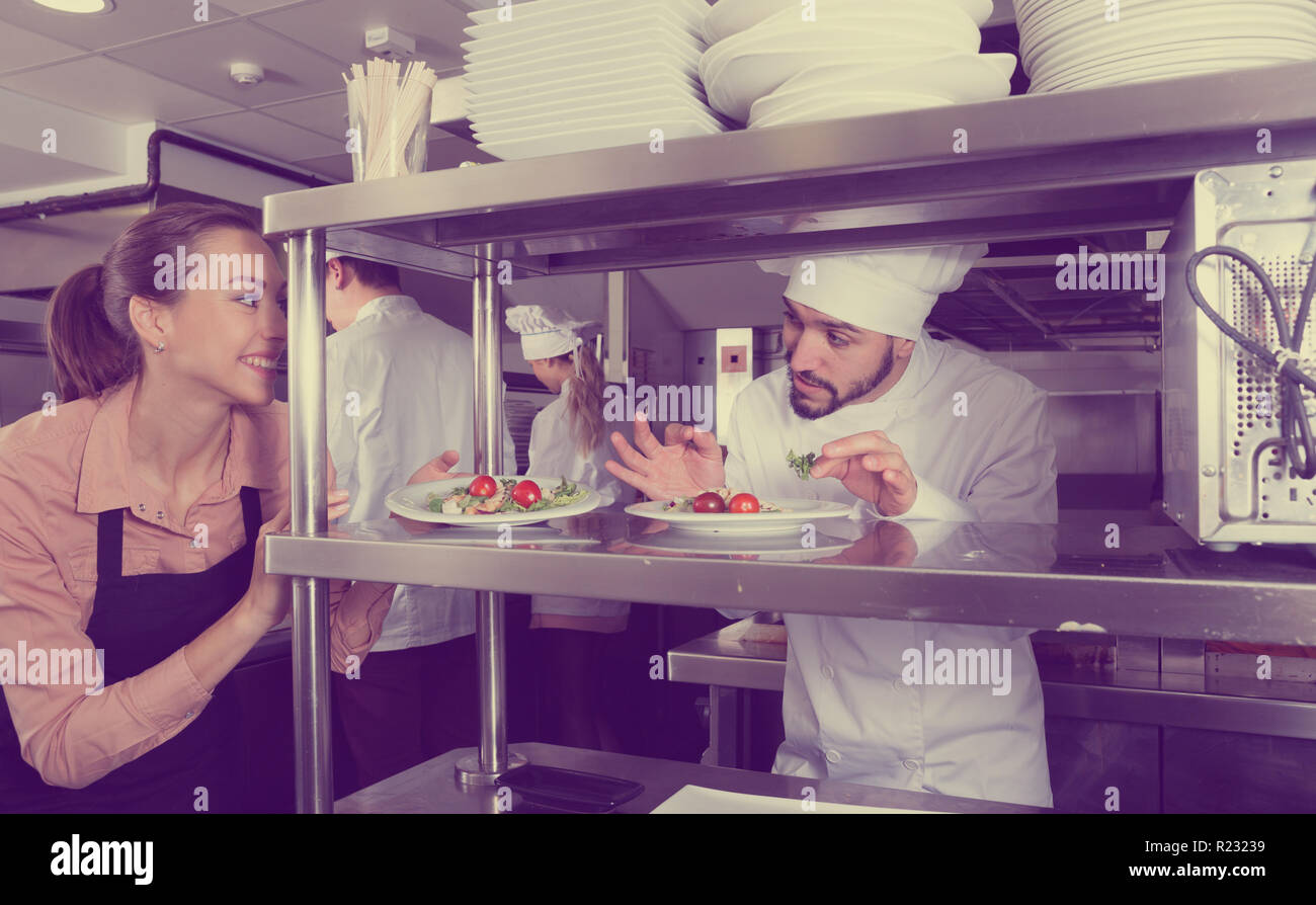 Head chef checking dishes in kitchen of restaurant before serving