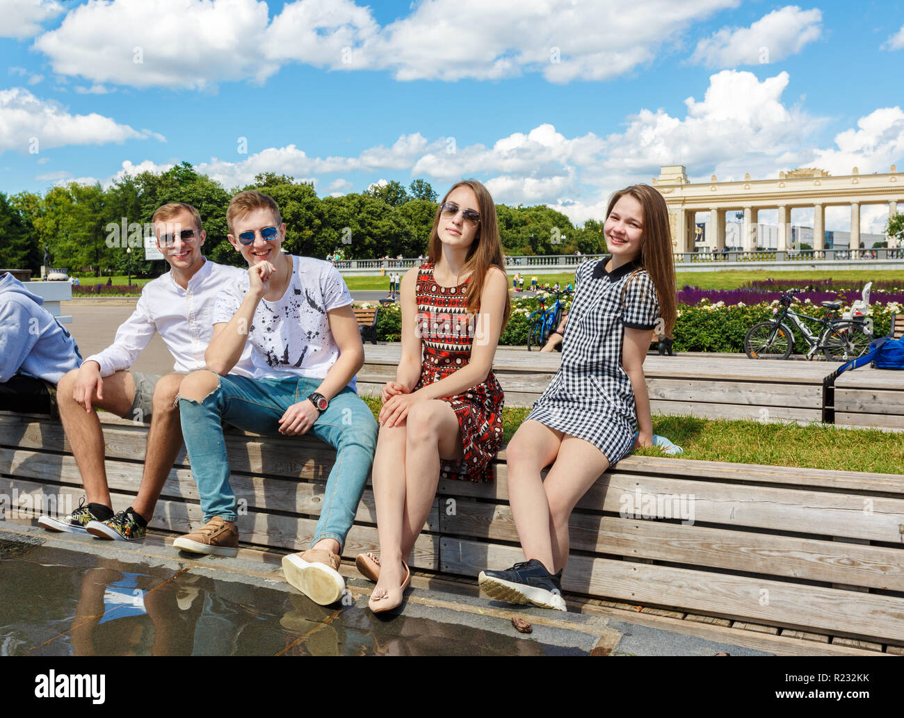 Group Of Young Friends Sitting On A Park Bench Talking Stock Photo