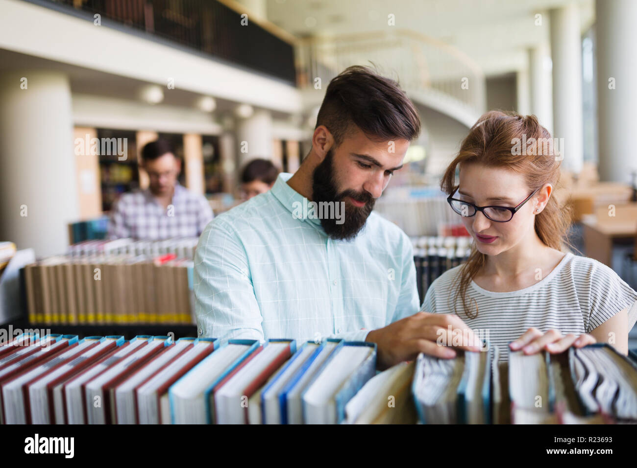 Happy young university students studying with books in library Stock ...