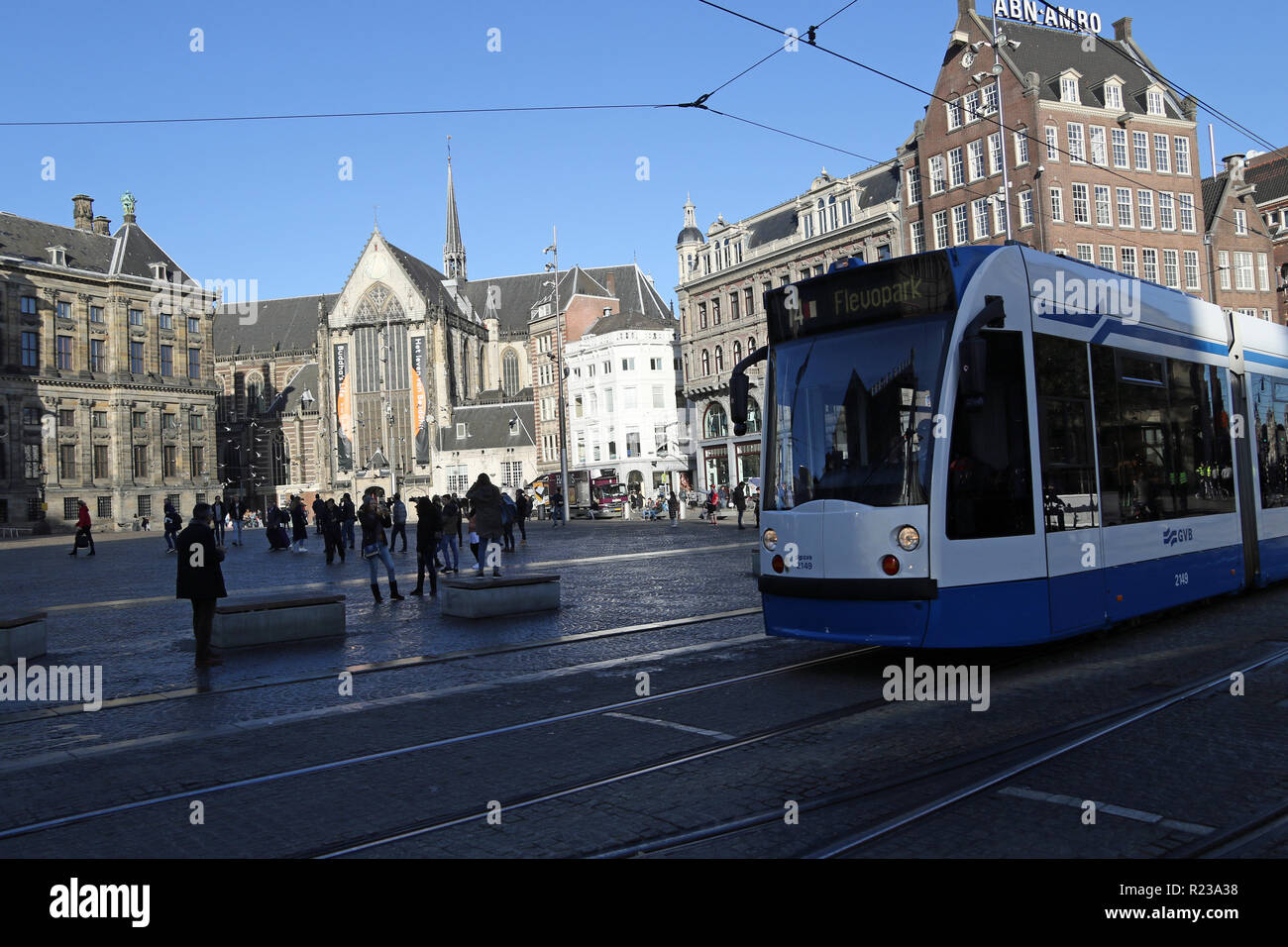 In Dam Square Amsterdam. In the distance is the Nieuwe Kerk is a 15th-century church, next to the Royal Palace. Formerly a Dutch Reformed Church parish, it now belongs to the Protestant Church in the Netherlands. In the foreground is a tram on the network. Stock Photo