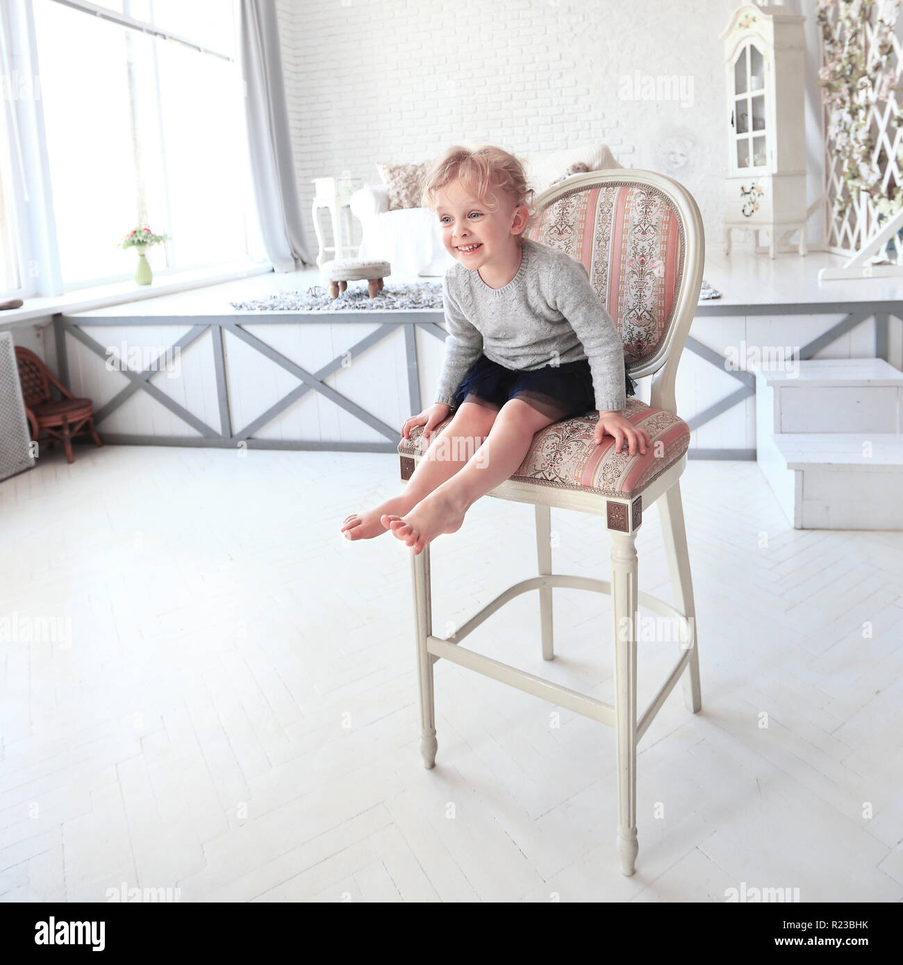portrait of happy little girl sitting on a chair in the spacious Stock ...