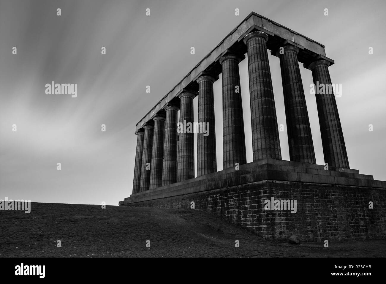 Clouds blur as they're blow across Calton Hill and the unfinished National Monument of Scotland building in Edinburgh at night. Stock Photo