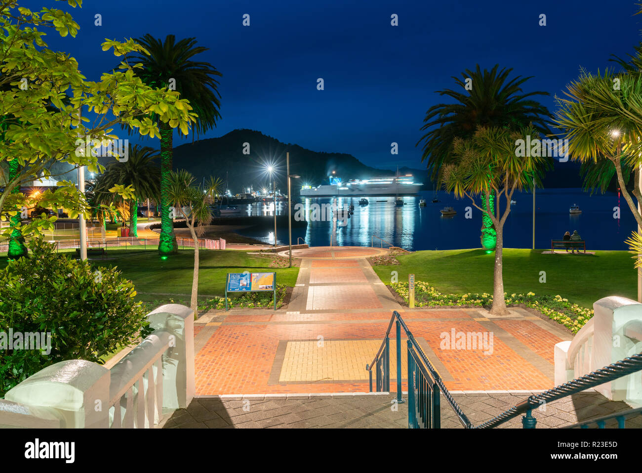 PICTON NEW ZEALAND- OCTOBER 2 2018; waterfront at night with illuminated past to watersedge and blurred ferry moving out of harbor. Stock Photo