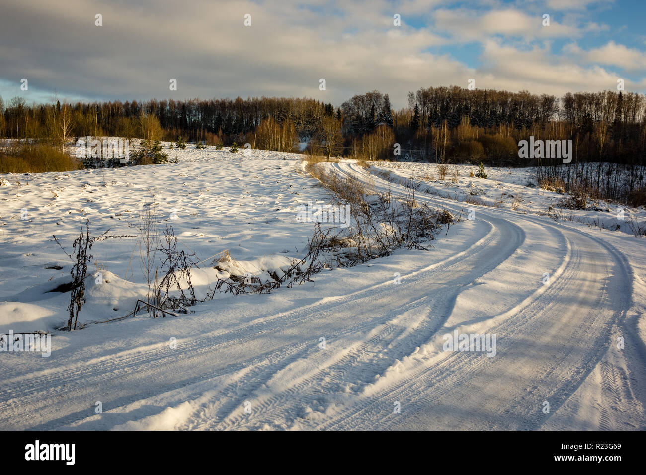 snow and ice covered road in countryside in winter with tire tracks ...