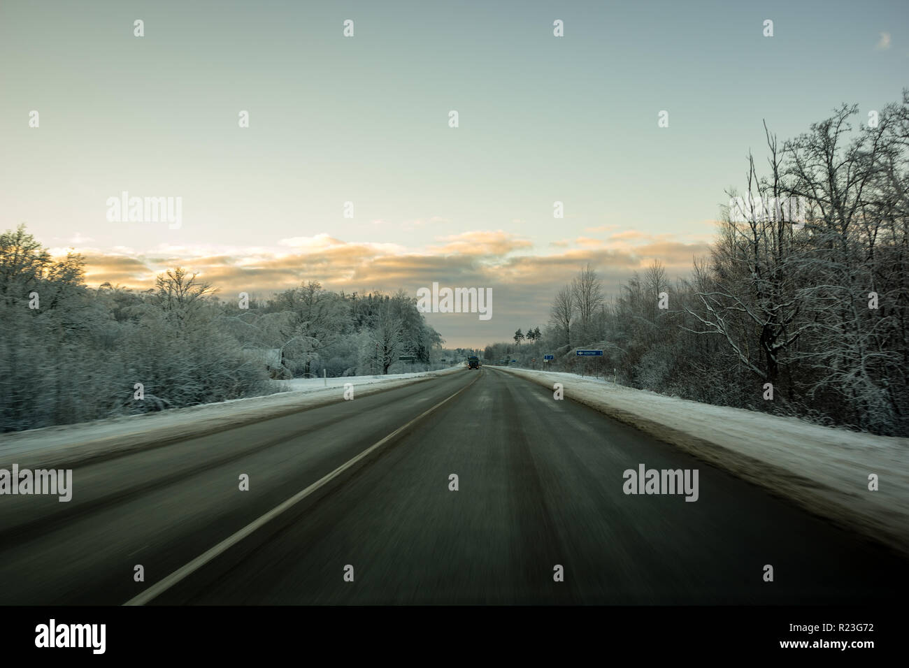 snow and ice covered road in countryside in winter with tire tracks ...