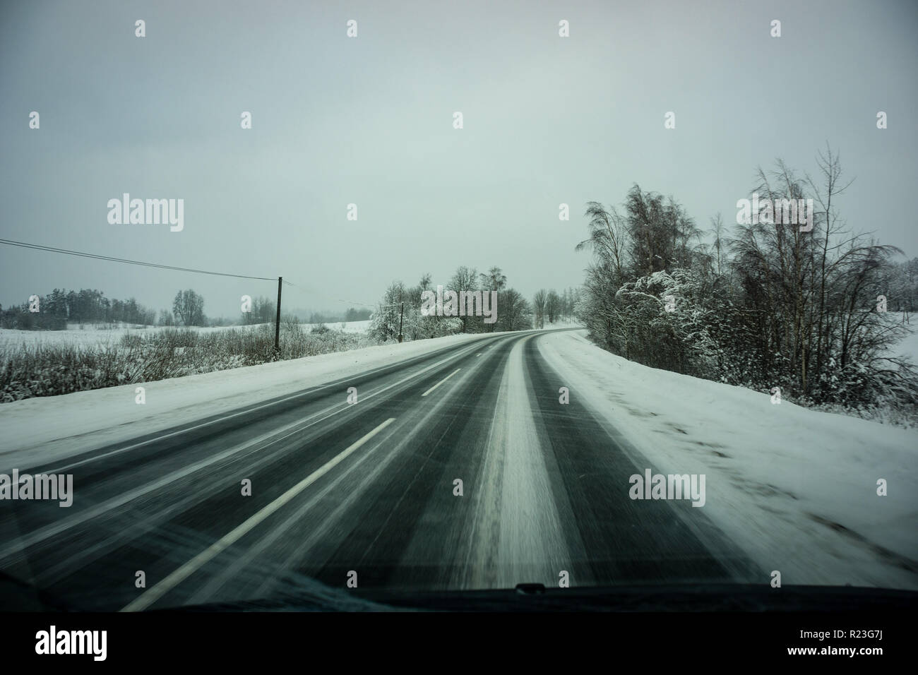 snow and ice covered road in countryside in winter with tire tracks ...