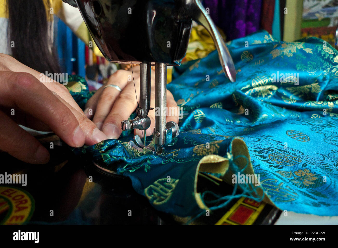 India, Himachal Pradesh, Manali, Gandhan Thekchokling Gompa, 08/09/2010: a woman sews a blue dress with a sewing machine in the tailor shop of the Bud Stock Photo