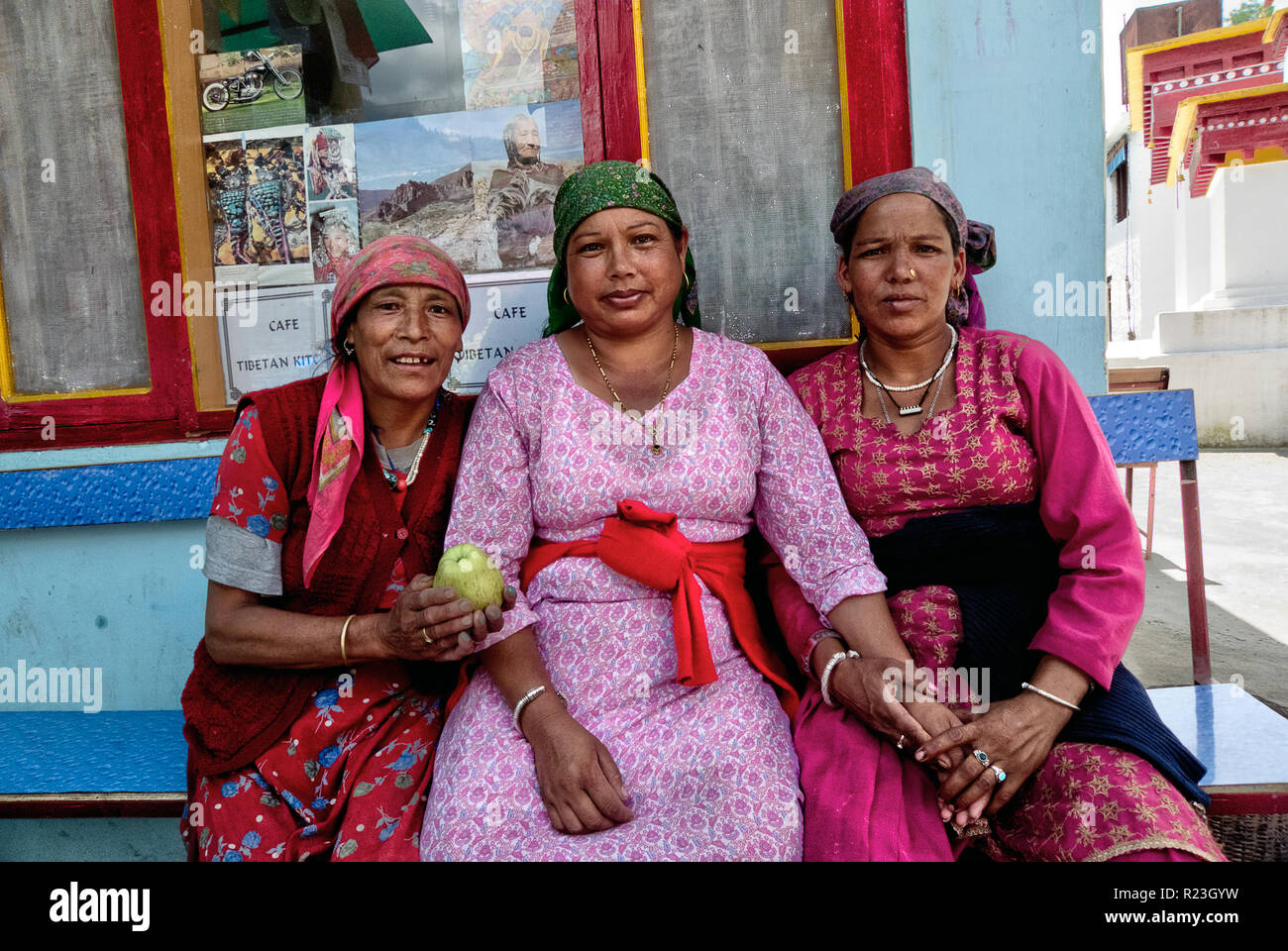 India, Himachal Pradesh, Manali, Gandhan Thekchokling Gompa, 08/09/2010: three women sitting on a bench hold hands and one of them shows an apple Stock Photo