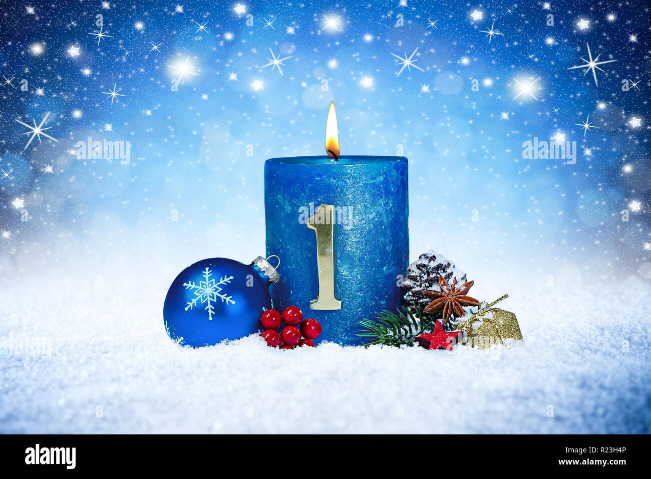 first sunday of advent blue candle with golden metal number red decoration one on wooden planks in snow front of silver panorama bokeh background Stock Photo