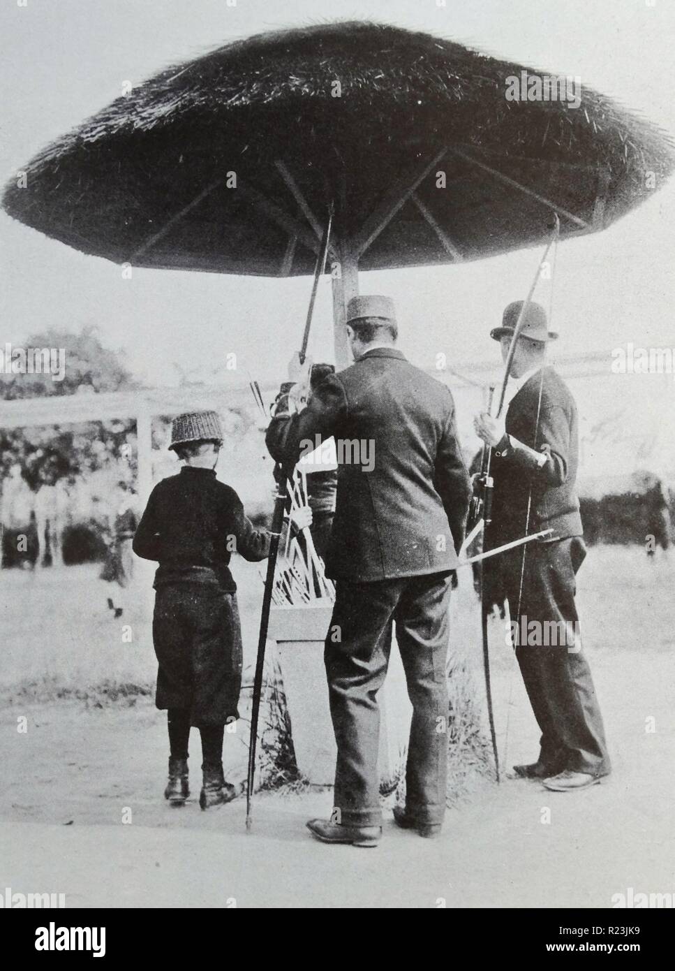 The mushroom head protector used in an archery contest, Belgium 1914. Under this structure we see two archers picking arrows for their next shot. The leather 'brassards' on their arms are supposed to protect their wrists against injury caused by the string when the arrow is released. Stock Photo