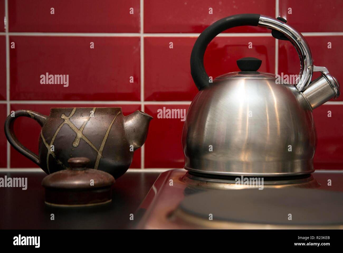 Stainless steel kettle on electric hob in London kitchen with teapot