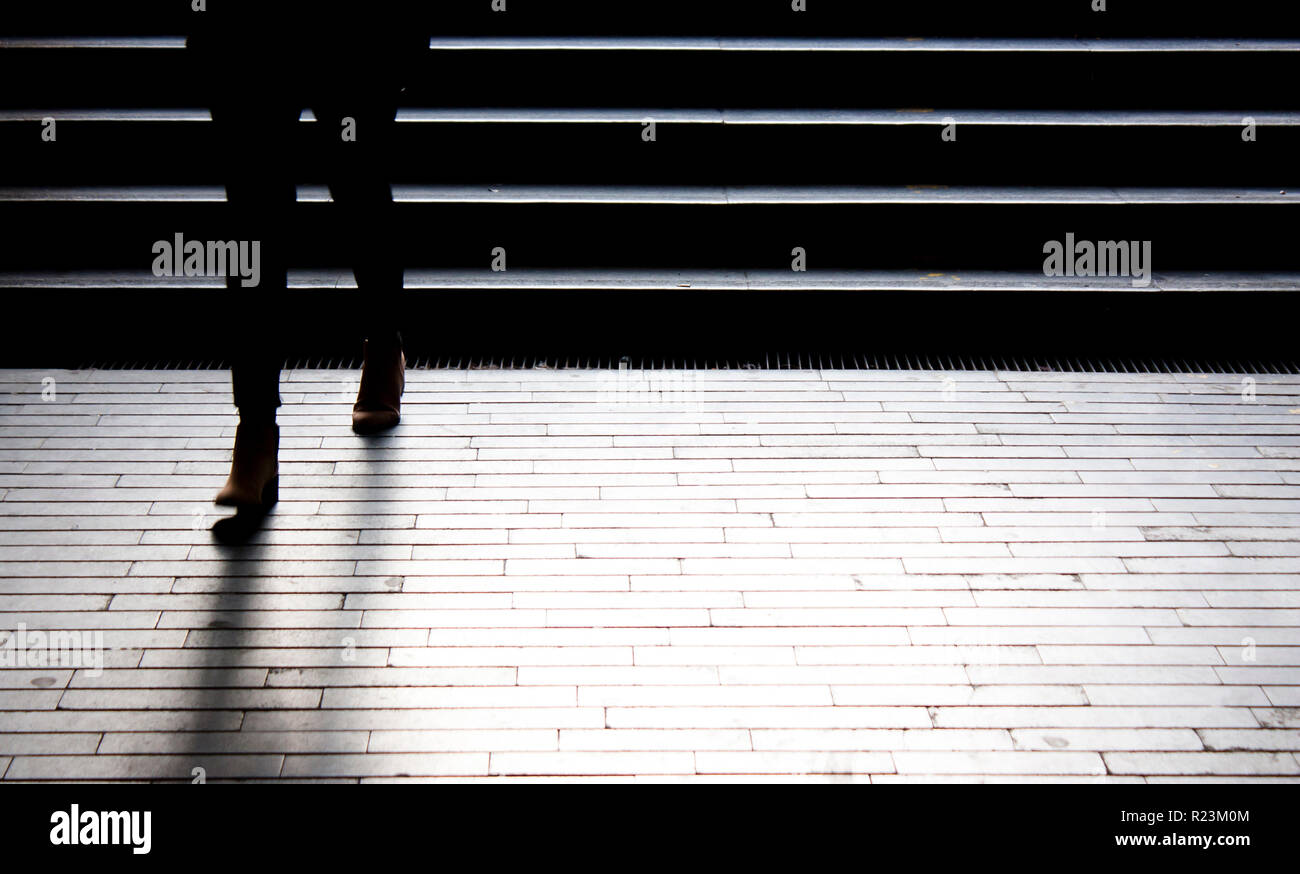 Person going down the dark city street stairs, legs in motion blur Stock Photo