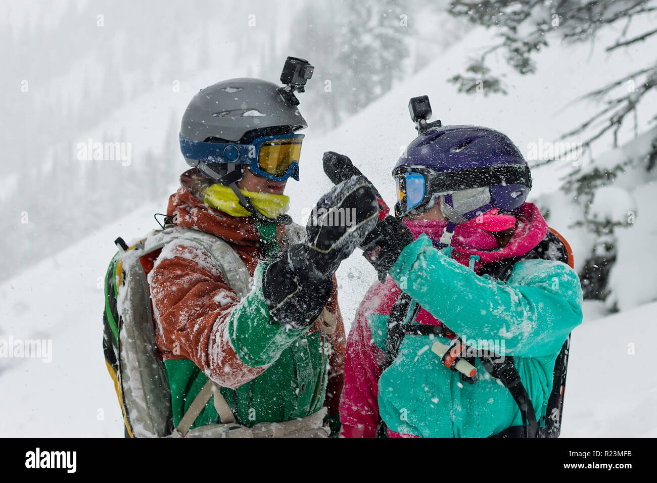 portrait of a pair of snowboarder freeriders wearing helmets in the snow give five Stock Photo