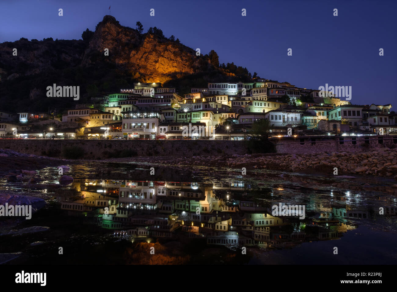 Night view of the houses of Berat, Albania known as the one thousand window city. Reflection of lights in river. Castle overviews the scene Stock Photo