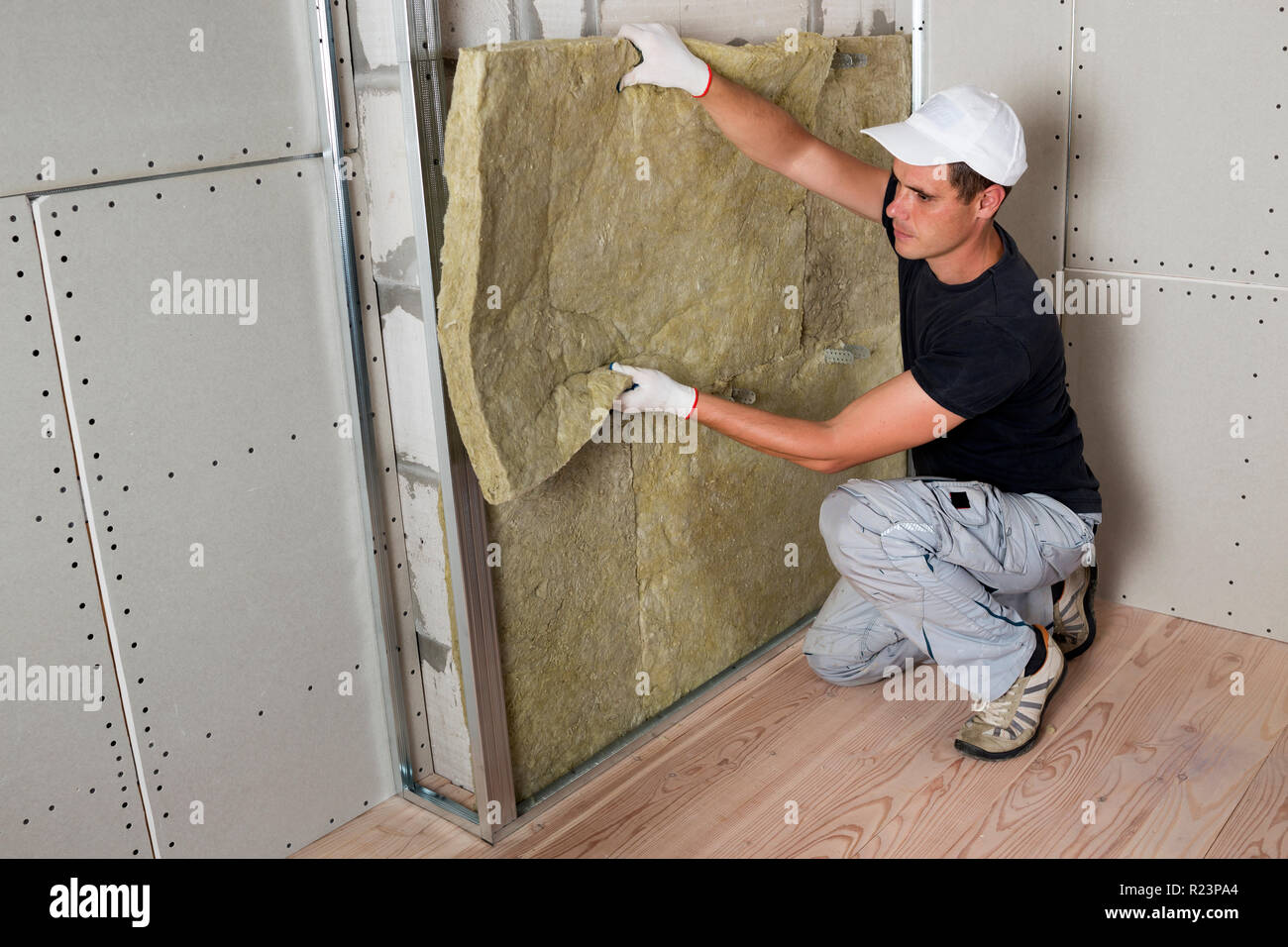 Worker insulating a room wall with mineral rock wool thermal insulation., Stock image