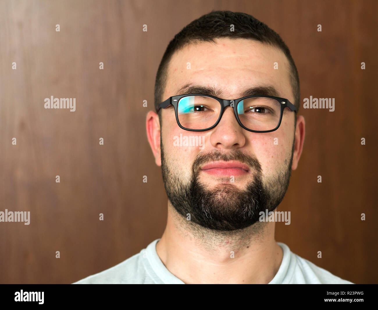 Portrait of handsome bearded black haired intelligent modern young man in  glasses with short haircut and kind black eyes smiling on blurred  background Stock Photo - Alamy