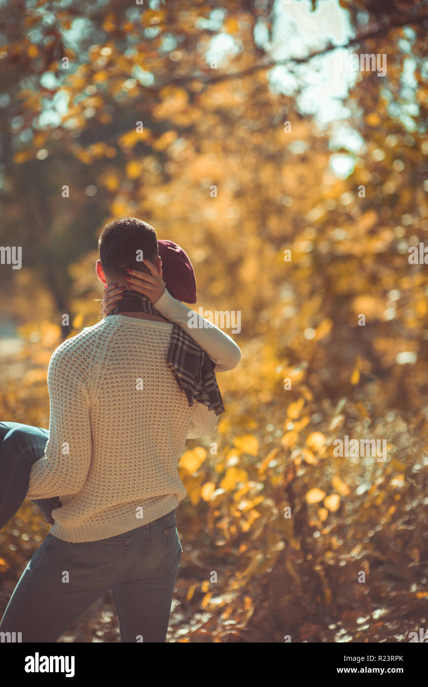 A couple is in the park and the girl is hugging her boyfriend while he ...