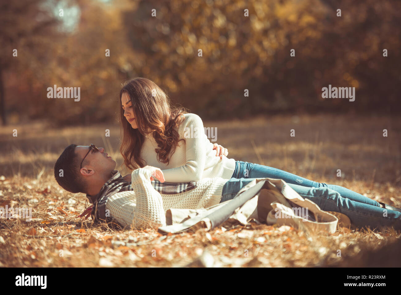 Cute couple is lying on the ground in the park on the colorful autumn leaves Stock Photo