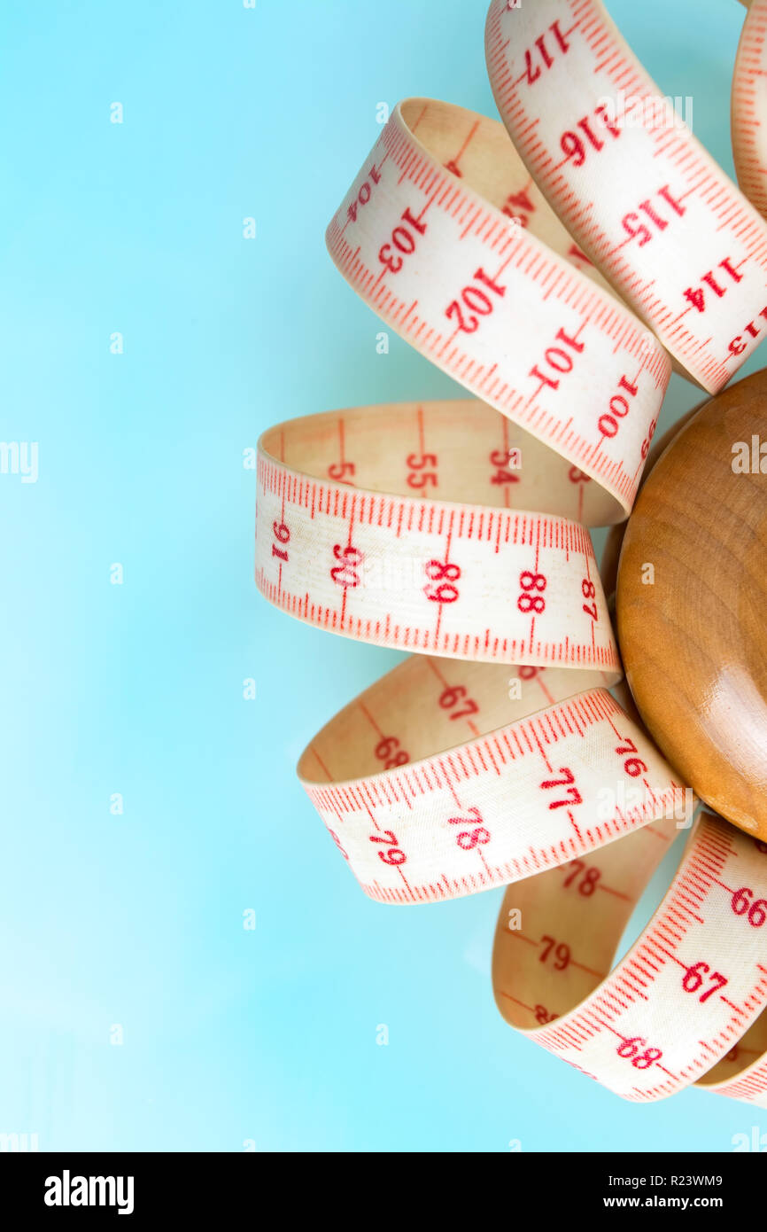 Yoyo effect in diet concept. Wooden yoyo with centimeter measure. Vertical orientation. Blue