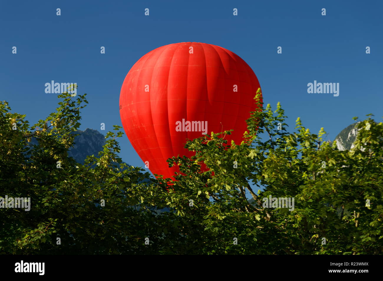 Red balloon flying over trees on an early morning flight over Lake Annecy France Stock Photo