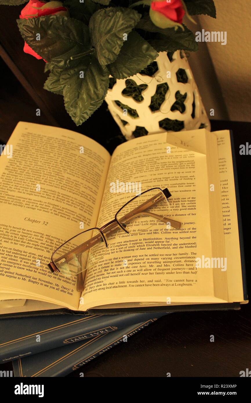 Open dog eared book with glasses Stock Photo