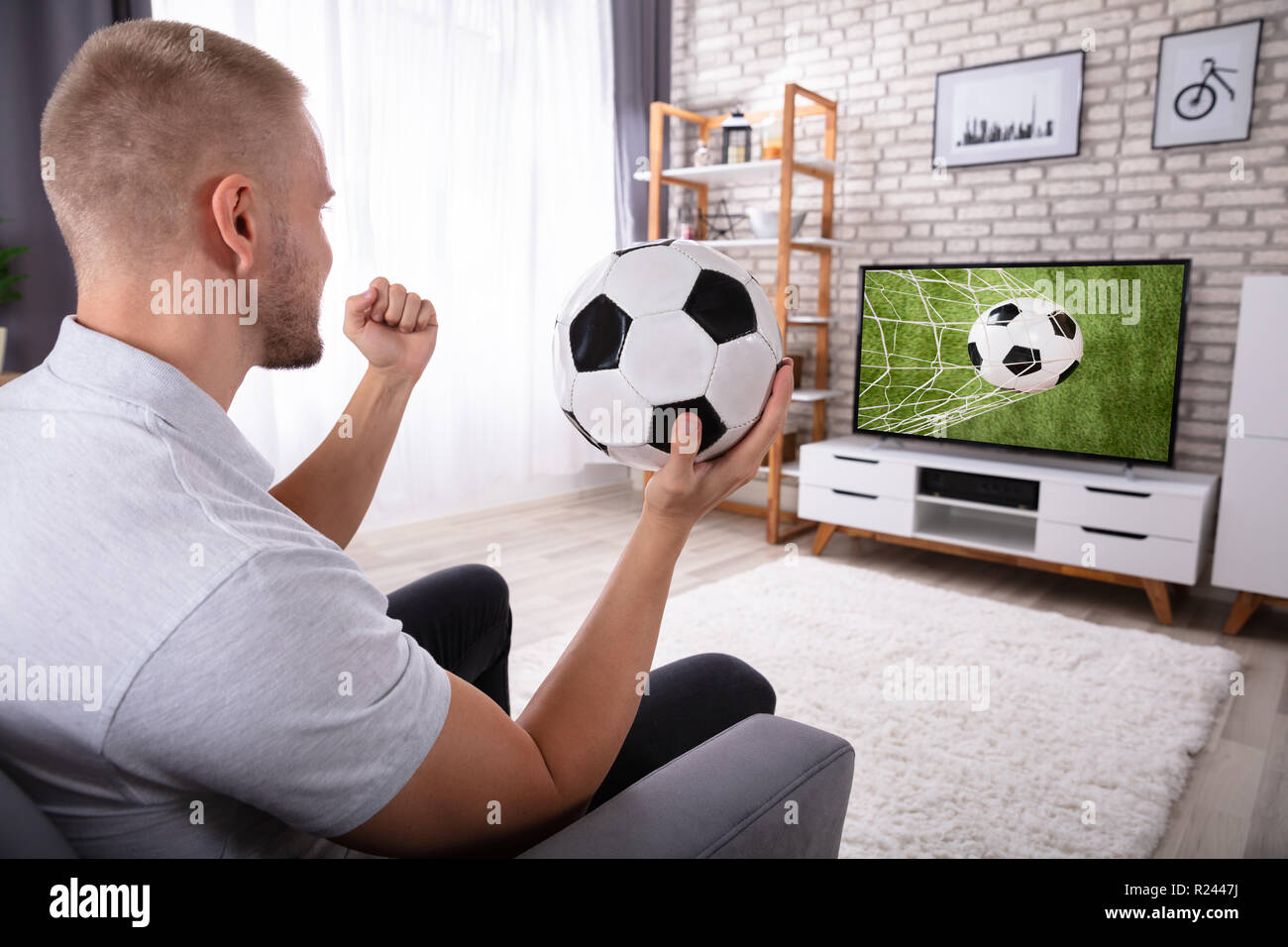 Excited Man Enjoying Football Match On Television At Home Stock Photo