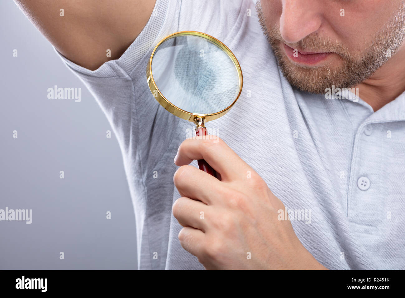 Close-up Of A Man Looking At Sweaty Armpit Through Magnifying Glass Stock Photo