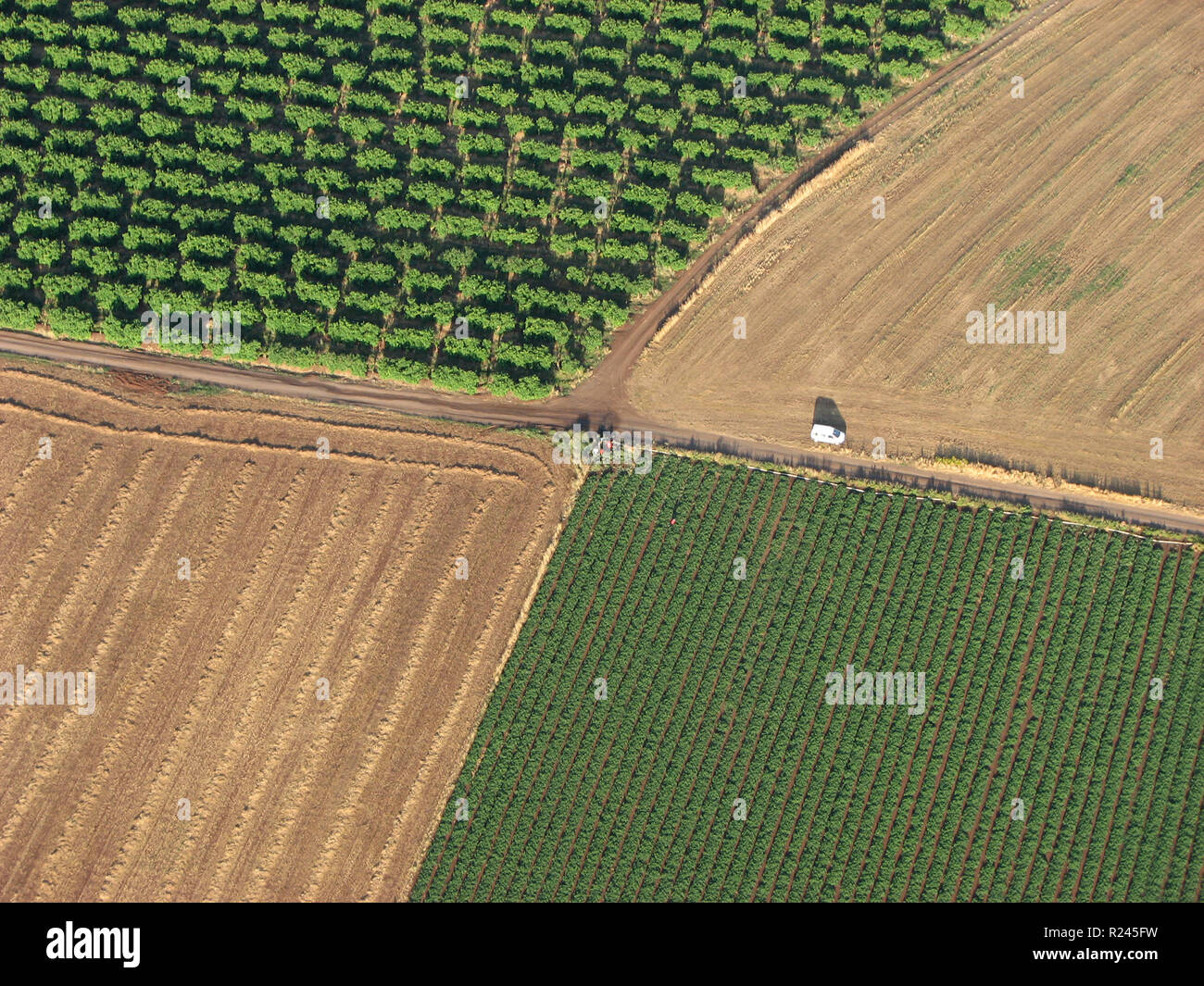 Aerial view of dirt roads intersection between Plowed fields and