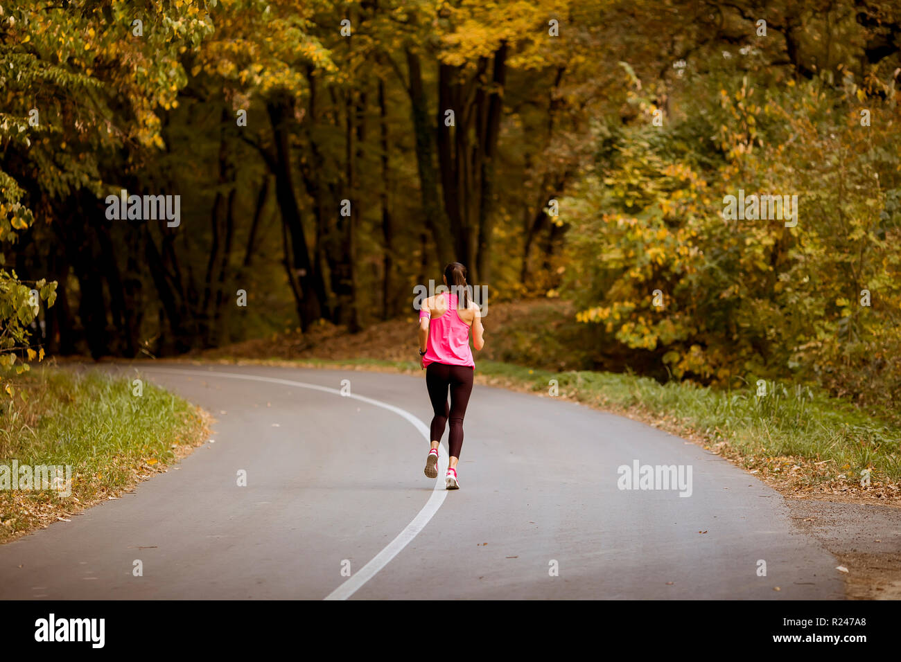 Young fitness woman running at forest trail in golden autumn Stock ...